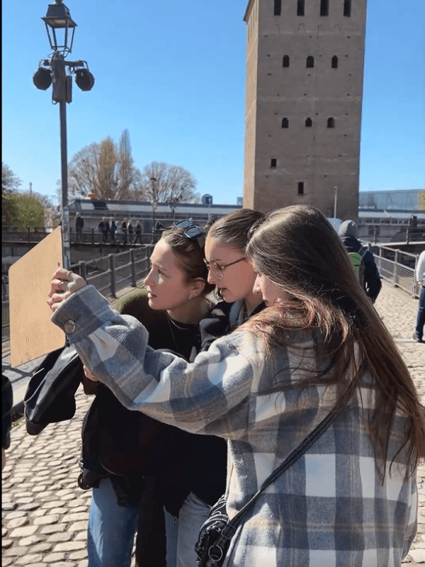 Trois joueuses consultent un smartphone près des Ponts Couverts lors de L’Héritage caché de la Petite France, aventure en autonomie des Secrets du Sablier pour découvrir la Petite France autrement.