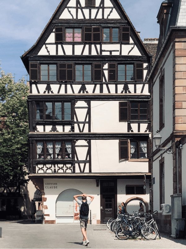 Participant en pleine réflexion lors du jeu "Les Gardiens de la Cathédrale", cherchant des indices numériques sur son smartphone, en immersion complète dans l’histoire et l’architecture de la Cathédrale de Strasbourg.