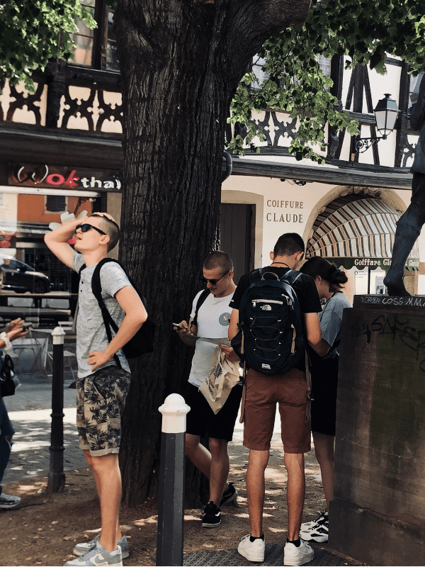 Groupe de joueurs suivant les indices du jeu de piste "Les Gardiens de la Cathédrale", en découvrant les secrets de Strasbourg et ses monuments historiques avec l’aide de leur smartphone, tout en explorant le patrimoine local.